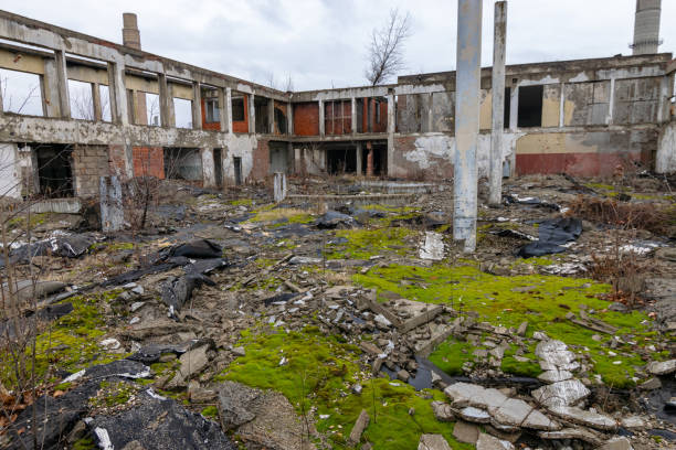 Halls of an old chemical factory looted dilapidated crumbling bricks gravel concrete moss tarpauline chimneys stock photo