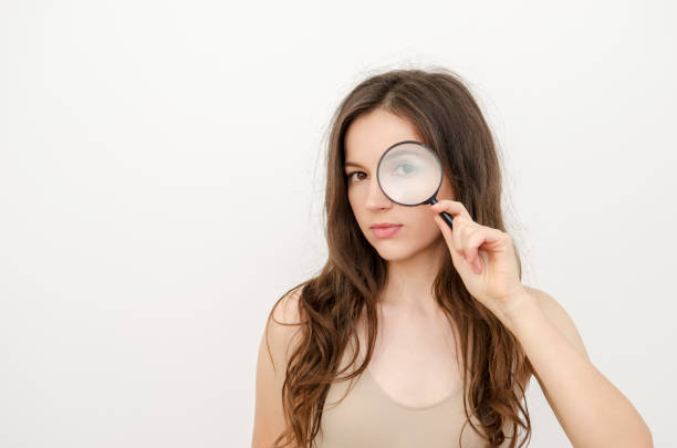 istock a woman looking through a magnifying glass 1456462388