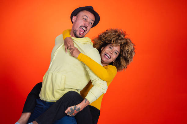 istock Couple of friends smiling and enjoying while standing on orange studio background 1456463801