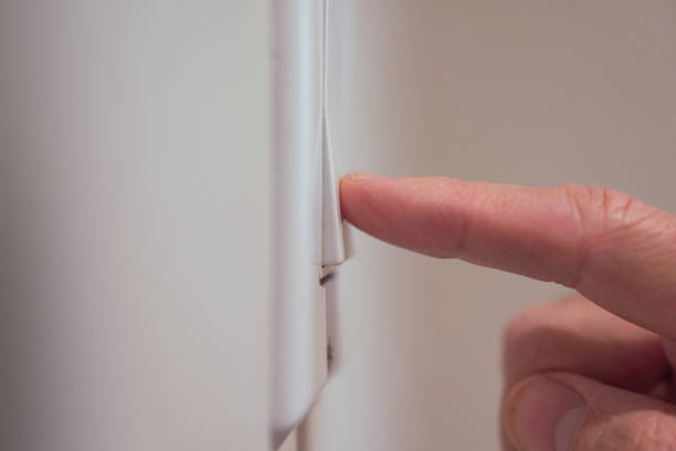 Closeup detail of male finger pushing light switch Extreme closeup of finger of male hand pushing light switch on wall light switch stock pictures, royalty-free photos & images