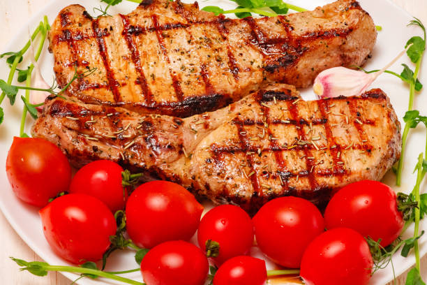 istock Two fried steaks in a plate with tomatoes. Meat with herbs, garlic and tomatoes. 1456464728