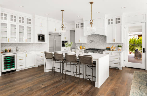 Beautiful kitchen in new farmhouse style luxury home with island, pendant lights, and hardwood floors. kitchen in newly constructed luxury home luxury stock pictures, royalty-free photos & images