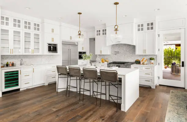 Photo of Beautiful kitchen in new farmhouse style luxury home with island, pendant lights, and hardwood floors.