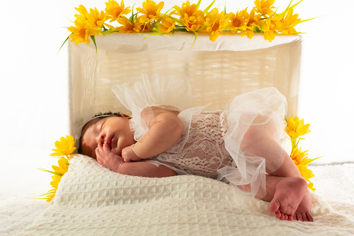 portrait of a newborn Hispanic baby girl in white clothes on a white background