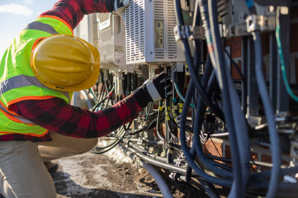 istock A blue-collar worker, a repairman, is checking and servicing telecommunication equipment mounted on a rooftop. 1456468188