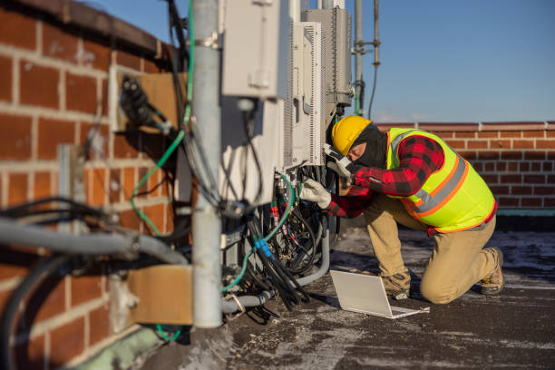 istock A blue-collar worker, a repairman, is checking and servicing telecommunication equipment mounted on a rooftop. 1456468190