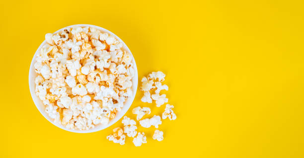 istock Scattered tasty cheese popcorn in bowl isolated on yellow background with copy space 1456473394