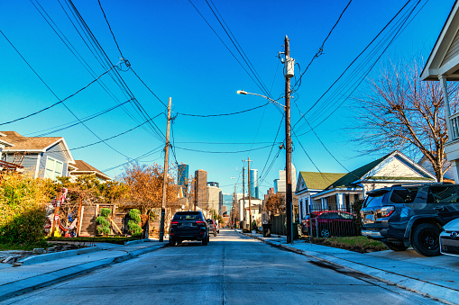 A residential street in the Midtown neighborhood of Houston, Texas leading toward the skyline of downtown.