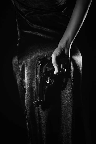 la silhouette d’une femme détective en robe avec un pistolet à la main, qu’elle cache derrière son dos. un livre dramatique noir portrait dans le style des détectives des années 1950 et 60. - police crime gun gang member photos et images de collection