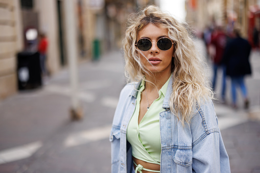 Close-up shot of beautiful young woman with sunglasses walking in the city