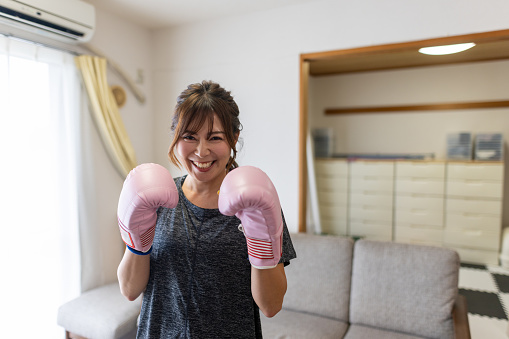 Portrait of happy woman exercising boxing at home
