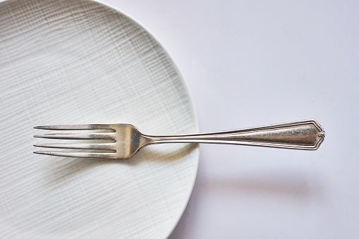 Dessert crumbs in white round plate with fork on yellow background, top view