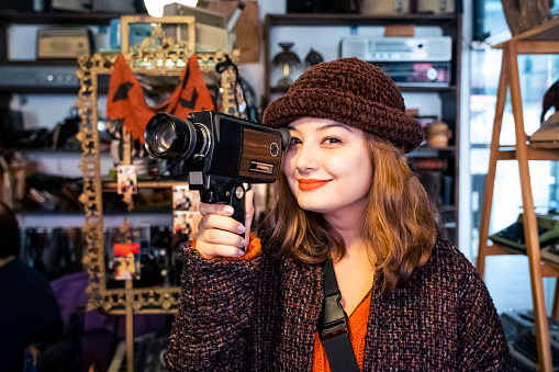 A young woman buys an old camera as a gift for her boyfriend from an antique shop