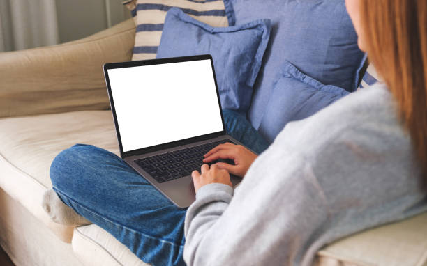 istock Mockup image of a woman working and typing on laptop computer with blank screen on sofa at home 1456509604