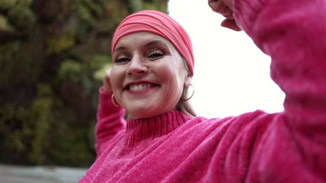 Portrait of hairless sick mature woman fighting cancer shows strength against disease, happy, feels optimistic, strong fight against oncology, health care concept