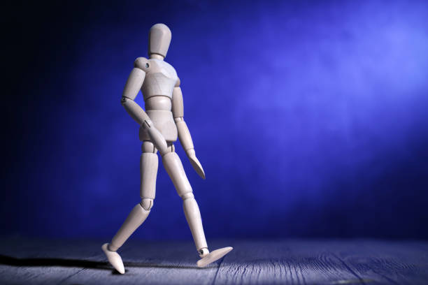 Wooden man doll walking under the light, against blue background