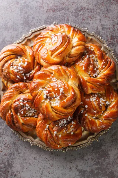 Swedish kanelbullar cinnamon buns made with a perfectly soft and chewy cardamom dough, a buttery cinnamon-sugar filling, and twisted into cute little knots close-up. Vertical top view from above