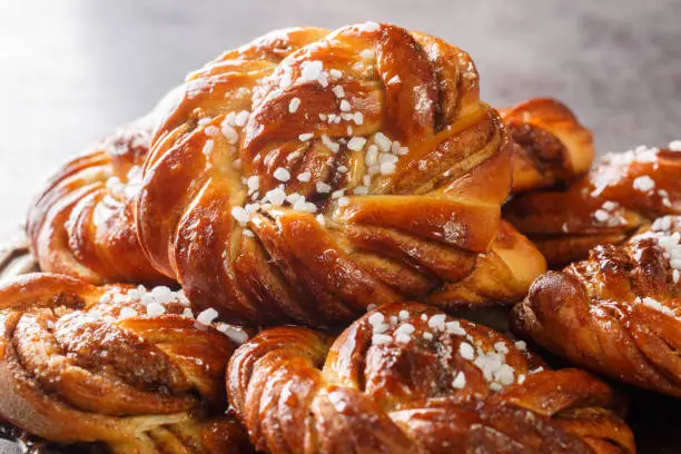 Swedish kanelbullar cinnamon buns made with a perfectly soft and chewy cardamom dough, a buttery cinnamon-sugar filling, and twisted into cute little knots close-up on a plate. Horizontal