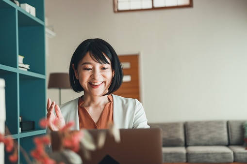 Asian mature worker using laptop in office.  Female CEO talking by online.