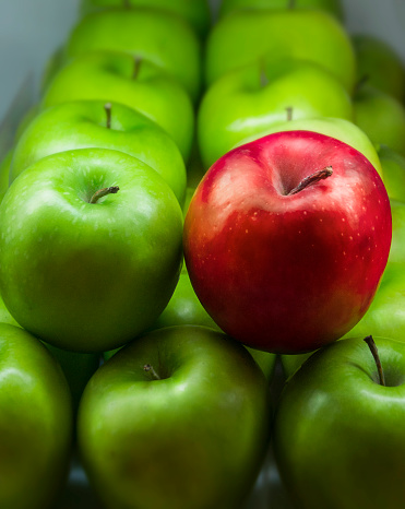 I saw these apples in the supermarket. It s interesting, the red apple stands alone among the green apples.