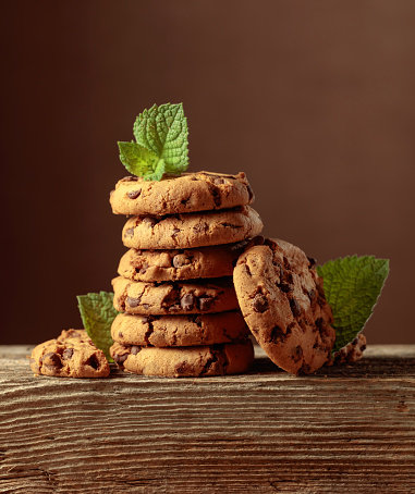 Freshly baked chocolate cookies with mint on an old wooden table. Copy space.