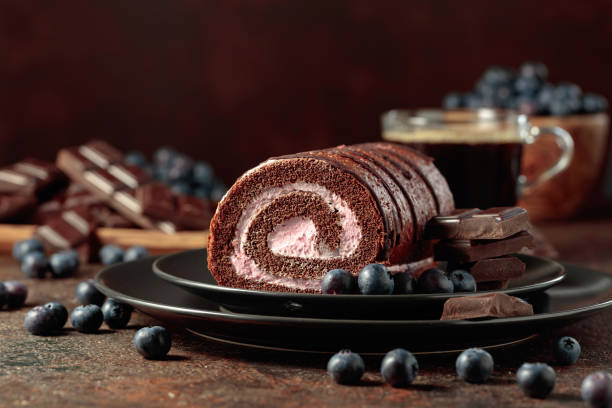 Chocolate roll cake with blueberries and a broken chocolate bar.