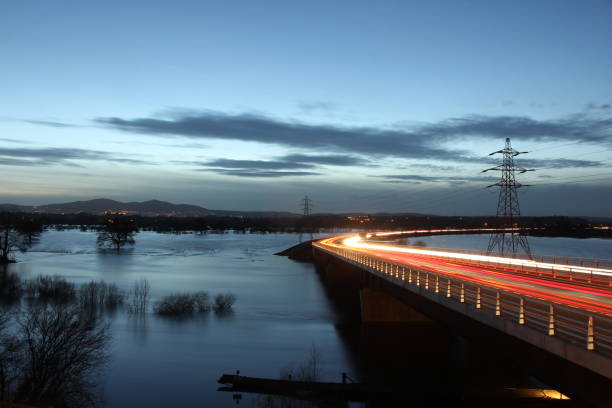 Flooding on Worcester floodplain with Malvern Hills in background and traffic light trails over Carrington Bridge
