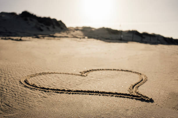 Drawing heart shape with footprints on the beach