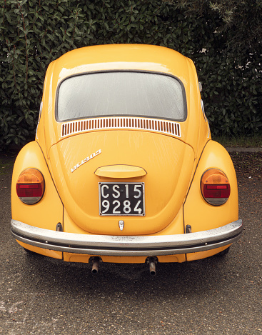 Cenaia, Italy - January 8, 2023: a beautiful Volkswagen Beetle, painted in rich yellow, is parked in a residential area in the province of Pisa