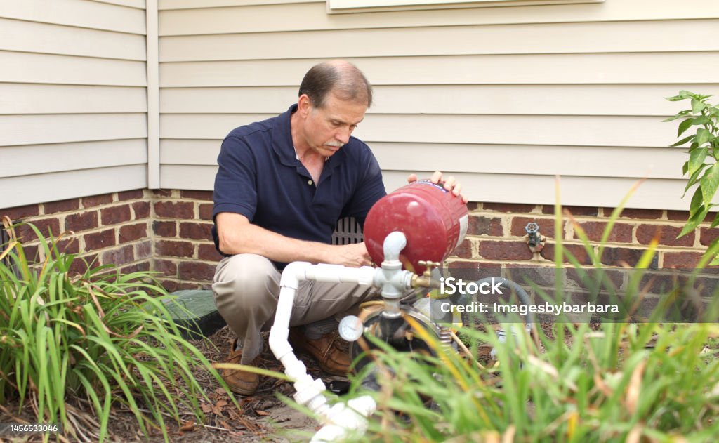 Well pump Senior male working on a well pump on his home Well - Structure Stock Photo