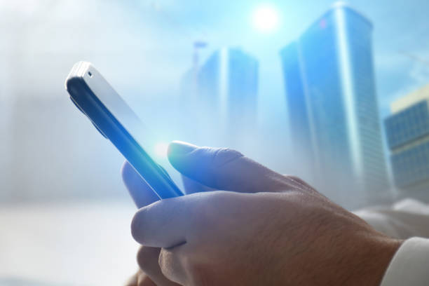 Using smart phone. A male hand text messaging with smart phone in the office. Financial district background. Communication concept with smart phone and using internet