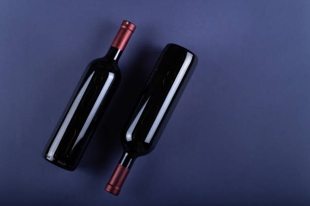 deux bouteilles de vin rouge sans étiquette sur fond de papier violet. maquette de boisson avec place pour vous étiquette et texte. - wine bottle wine wood bottle stopper photos et images de collection