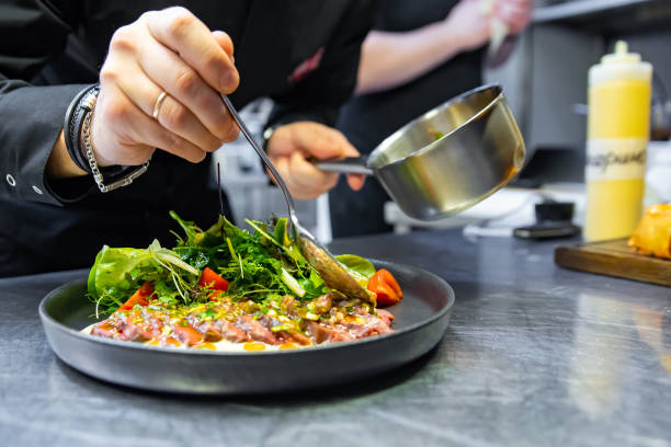 istock chef hand preparing Roastbeef salad with vegetables on restaurant kitchen 1456539839