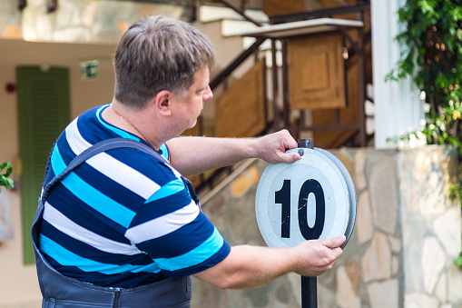 A man attaches a sign with the number of his house.