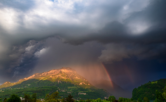 Storm front over the Alps mountains in Switzerland. Rain clouds and rainbow.