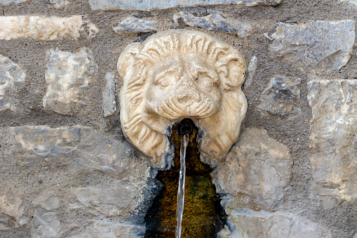 Source in the form of a lion's head with fresh, natural water in the village of Mistras near the mountains Taygetus (Greece, Peloponnese)