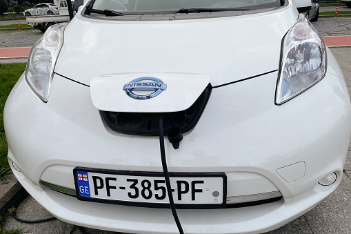 Power cable in electric car is charged from the wire, EV vehicle on the street, with modern technology, eco energy, Georgia, Batumi, December 15, 2022