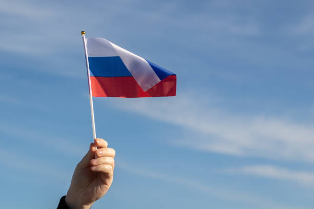 istock Russian flag in hand flutters in the wind against the sky 1456544757