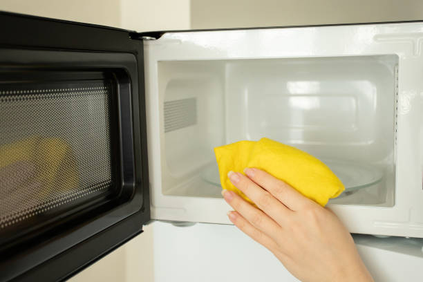 istock a woman's hand washes a microwave in the kitchen with a rag 1456544864