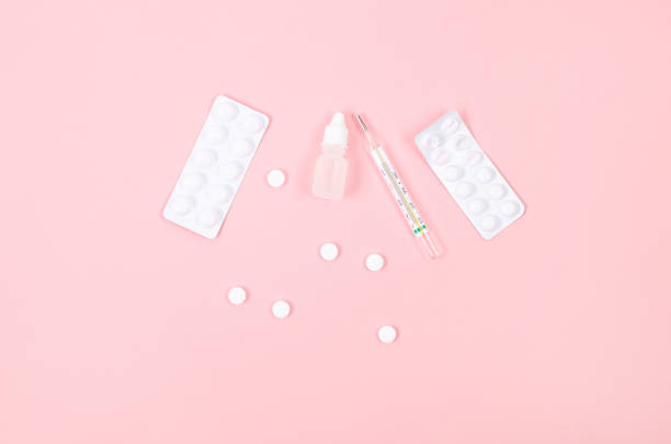 istock Pink background with pills, thermometer, spray bottles, blister, flat lay. 1456545169