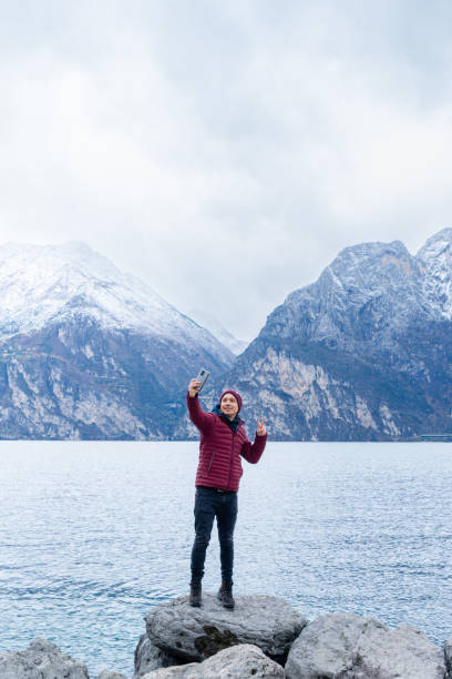 A boy takes a selfie with the snowy mountains behind him stock photo