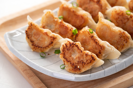 Taiwanese and Japanese Pan-fried gyoza dumpling jiaozi food in a plate with soy sauce on white table background.