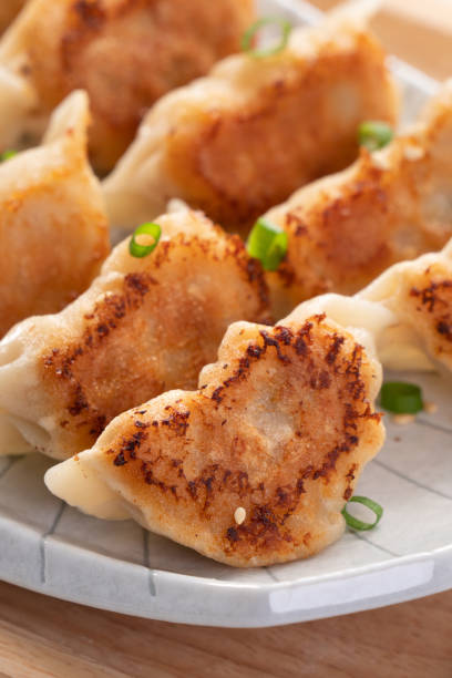 istock Pan-fried gyoza dumpling jiaozi in a plate with soy sauce on white table background. 1456547616