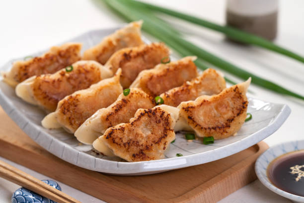 istock Pan-fried gyoza dumpling jiaozi in a plate with soy sauce on white table background. 1456547623
