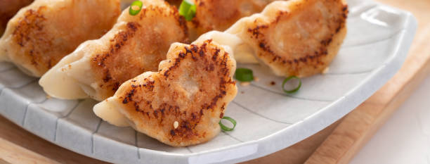 istock Pan-fried gyoza dumpling jiaozi in a plate with soy sauce on white table background. 1456547662