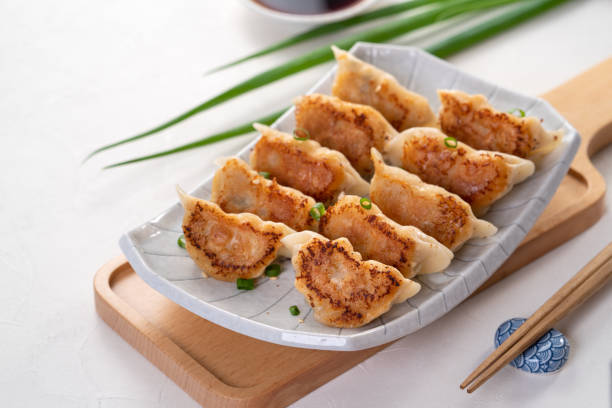 istock Pan-fried gyoza dumpling jiaozi in a plate with soy sauce on white table background. 1456547666