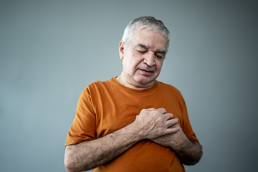 Senior man with hands on chest on a gray background