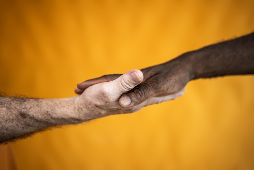 Two men's hands on an orange background