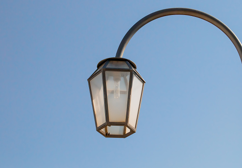An old street light set against a deep blue sky on a sunny summer day.