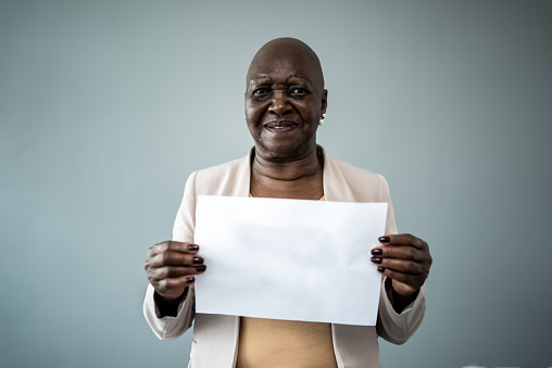 Portrait of a senior woman on holding a blank paper on a studio shot